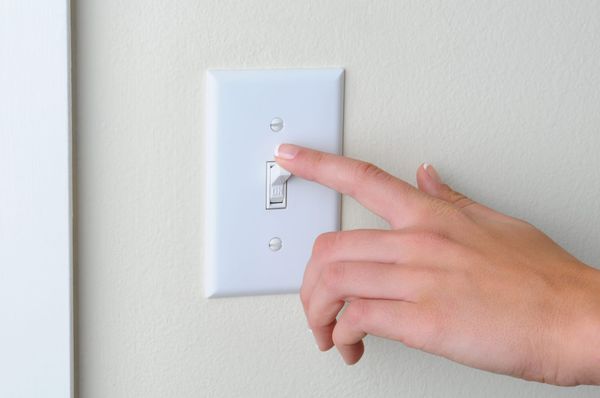 Hand turning light switch to "off" position