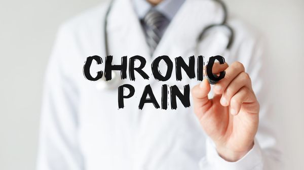 Reflection of doctor writing "Chronic Pain" on a mirror. 