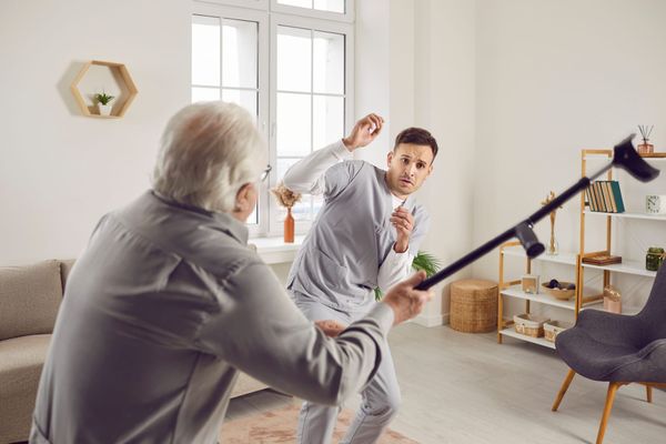 Elderly man brandishes his cane at cowering young health care worker 