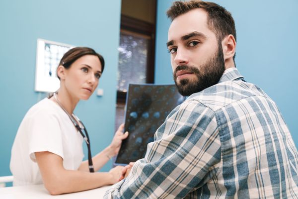 Female doctor explains brain scans to young man who looks back at camera