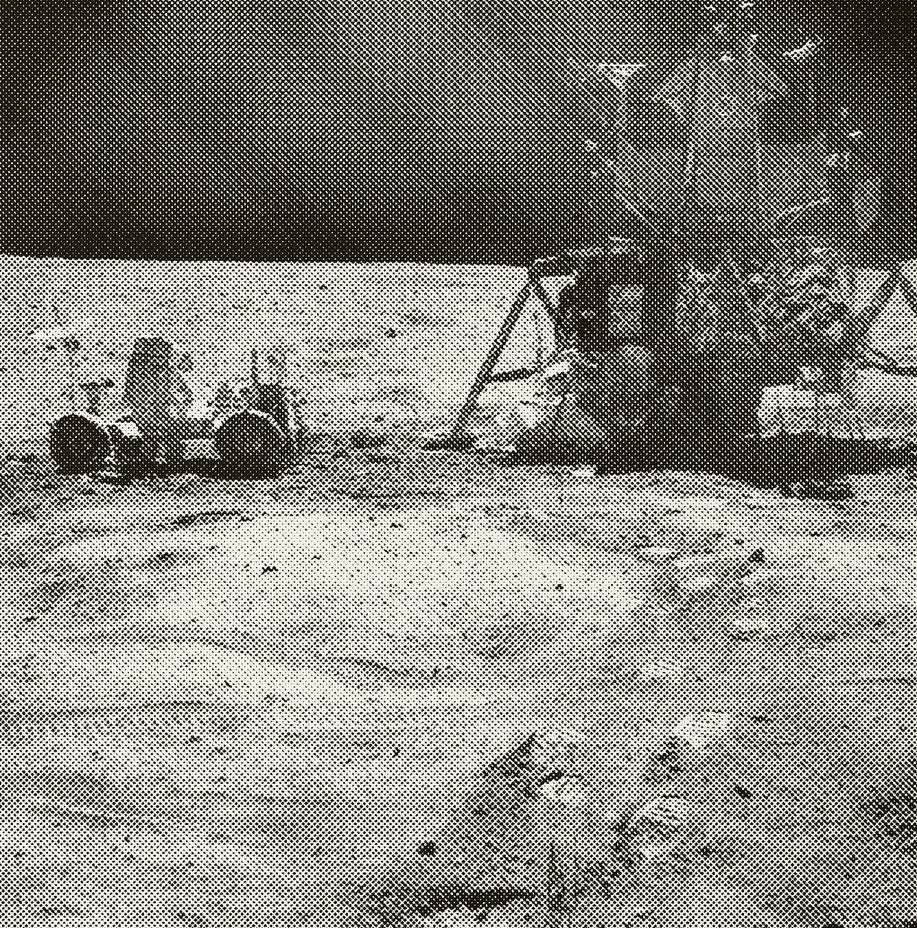 Newspaper-halftone reproduction of a NASA photograph from the Apollo 16 landing site. The lunar module Orion stands at right with the lunar roving vehicle parked at left, both small against a flat grey plain; the black sky sits hard above the horizon, and bootprints and rover tracks cross the foreground.