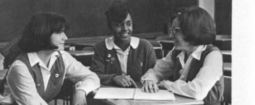 Three students of the Human Relations Club at the Academy of Holy Angels confer at a classroom table, 1966. The yearbook names them as Debbie Harper, Vivian Lasley and Sue Code.
