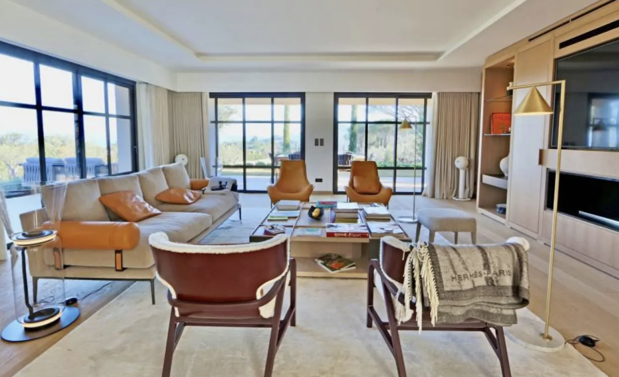 Villa Ella’s cozy living room featuring oversized windows, comfortable seating arrangement, and a modern table, creating an inviting atmosphere perfect for relaxation.