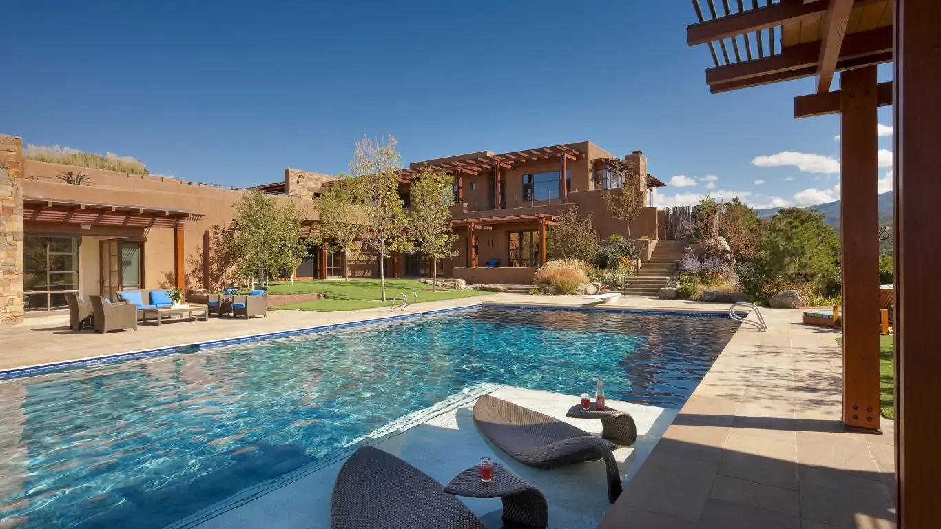 Immerse yourself in this desert-like estate featuring lush landscaping that surrounds a sleek swimming pool.