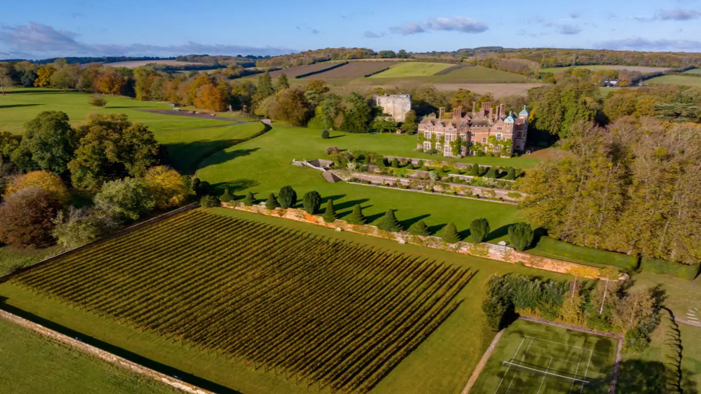 Aerial view of Chilham Castle, surrounded by verdant green hills and a meticulously maintained vineyard.