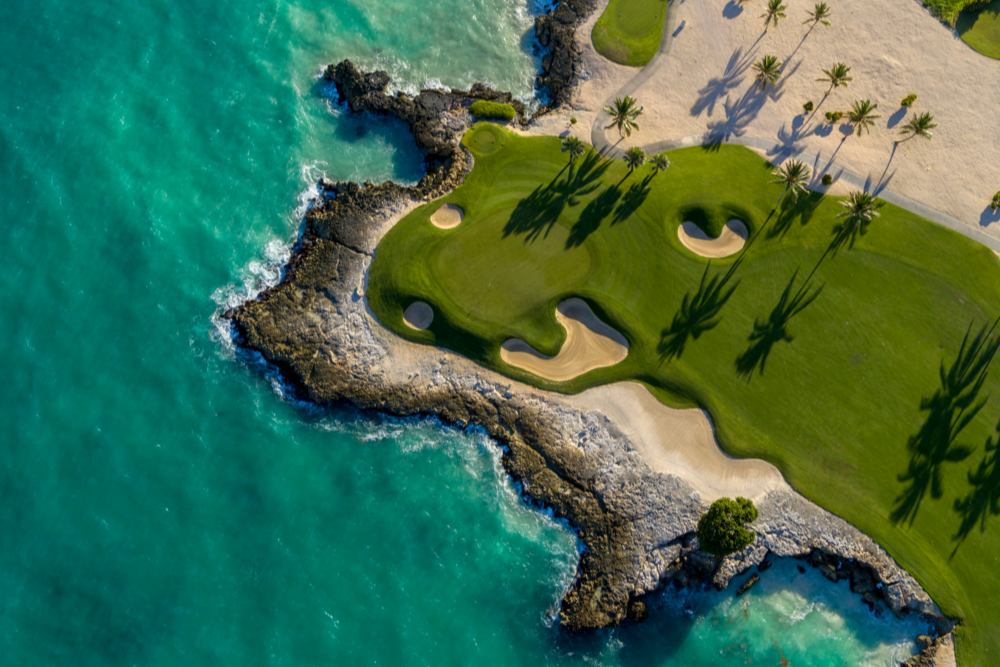 Aerial view of Punta Espada Golf Course in the Dominican Republic, featuring oceanfront fairways, sculpted bunkers, and palm-lined greens against the turquoise sea. A premier luxury golf destination.