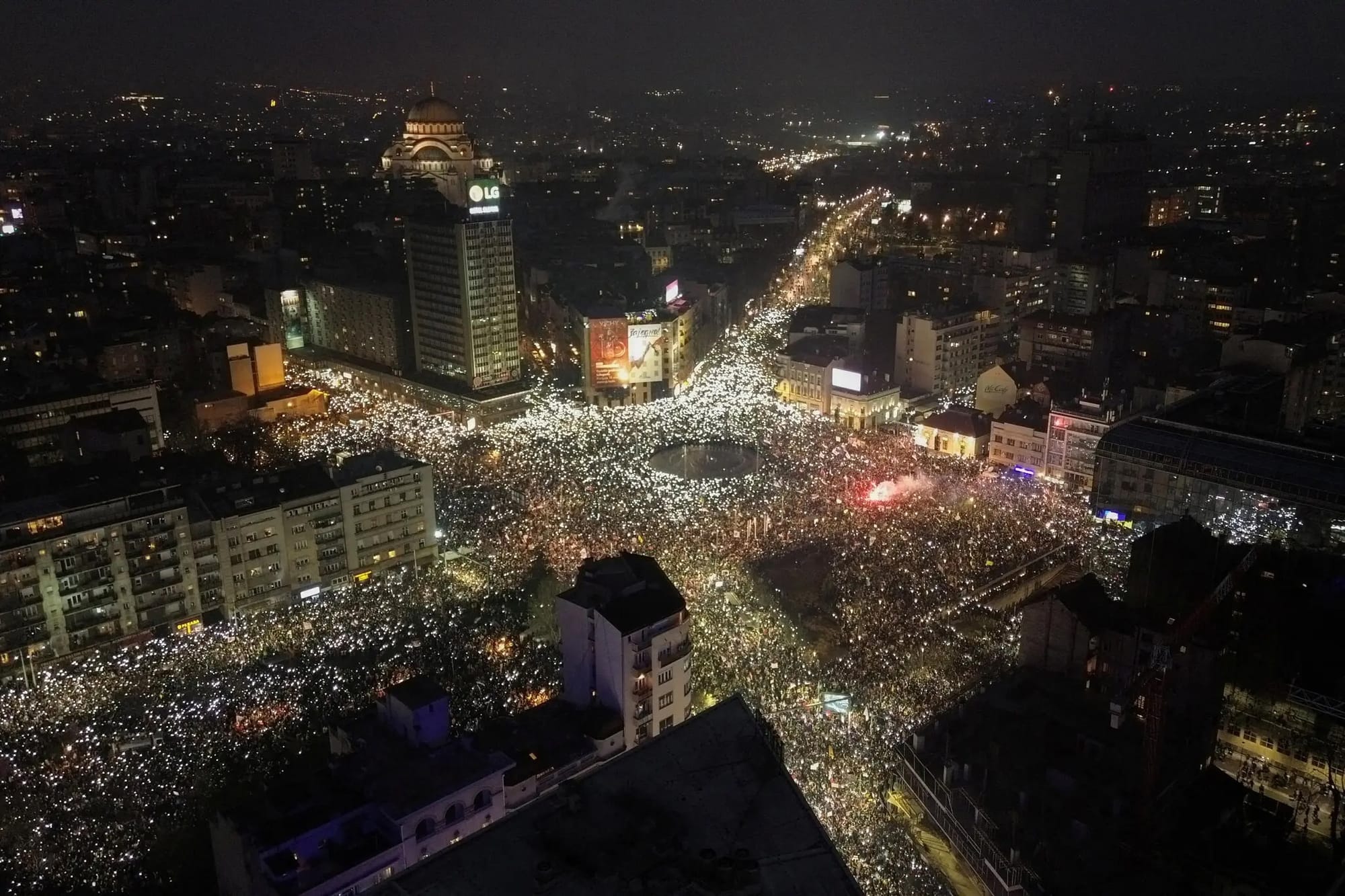 Hundreds of thousands of people gathering in a central square at night with their cell phone lights on.