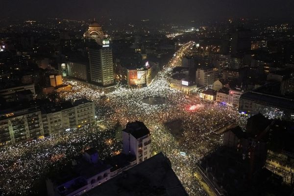 Hundreds of thousands of people gathering in a central square at night with their cell phone lights on.