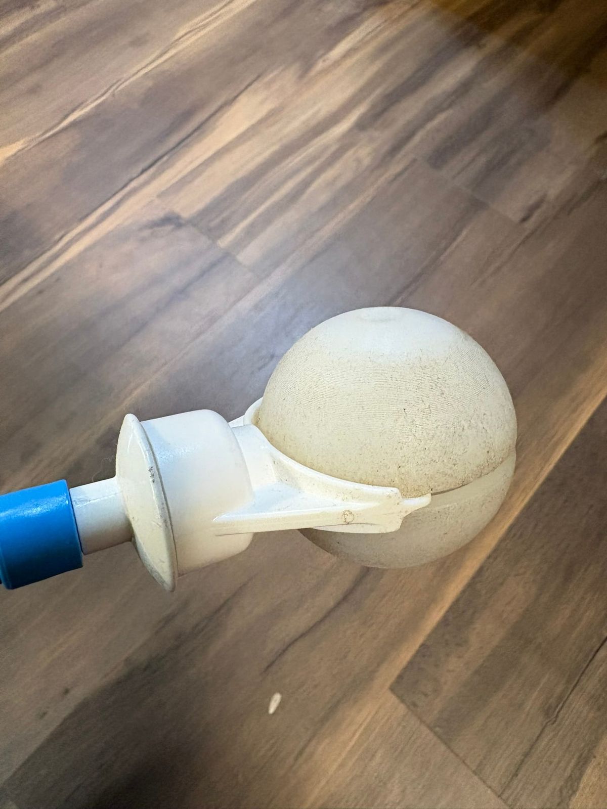 A closeup of the Ambutech Pathfinder 360 cane tip. It is dirty and a bit worn at the end of a cane that disappears from frame