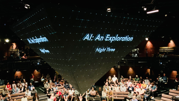 An inverted-pyramid screen glowing "AI: An Exploration, Night Three" above a masked, seated audience at London's Young Vic theater.