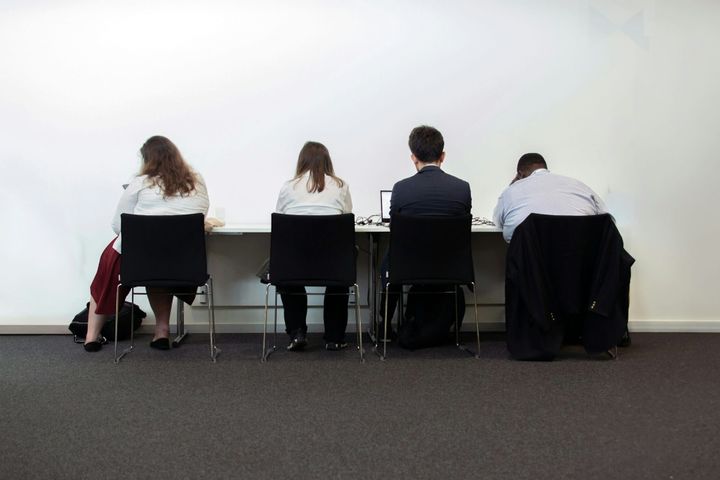 A group of people sitting at a table in front of a white wall