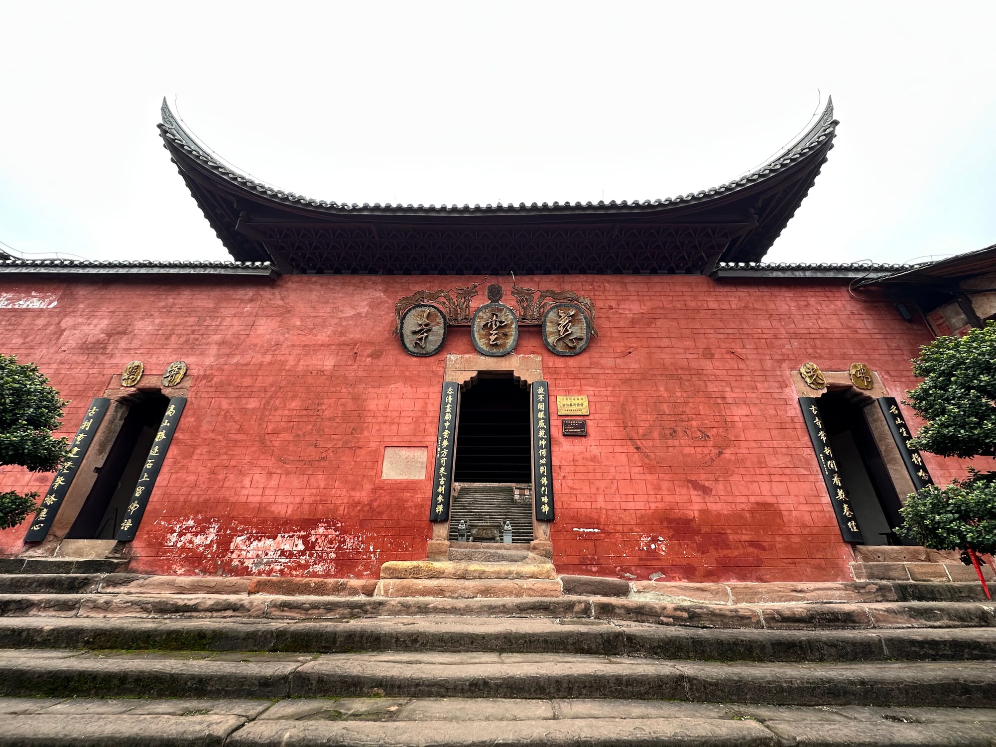 Traditional Chinese red brick temple with three doors atop a dilapidated set of stairs in Yaoba Historic Town in Sichuan, China