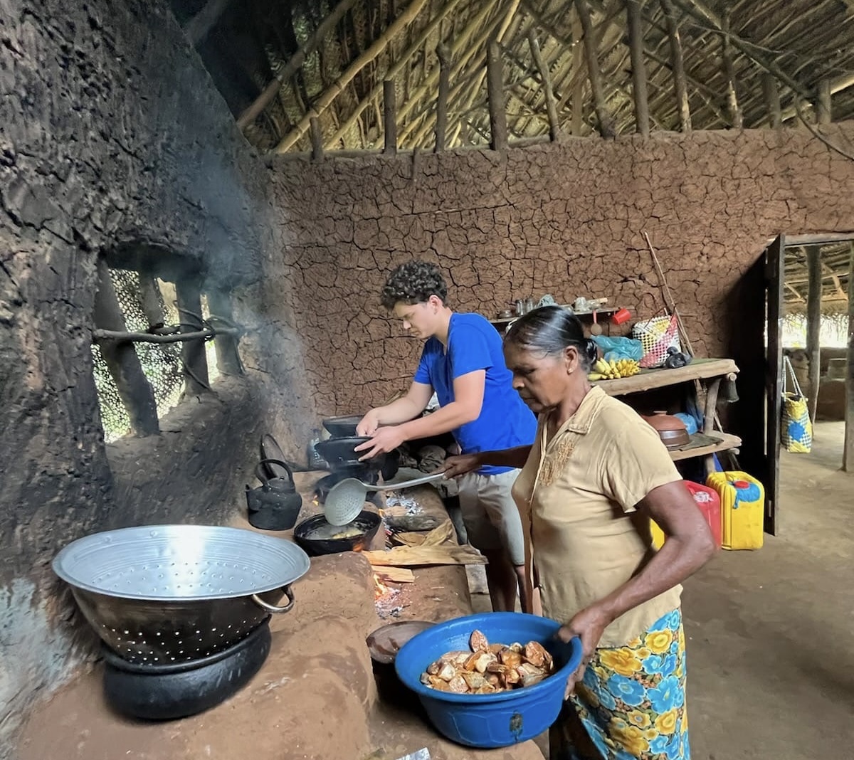 Arnold next to his aunt in their family's traditional Sri Lankan home, cooking over an open fire.