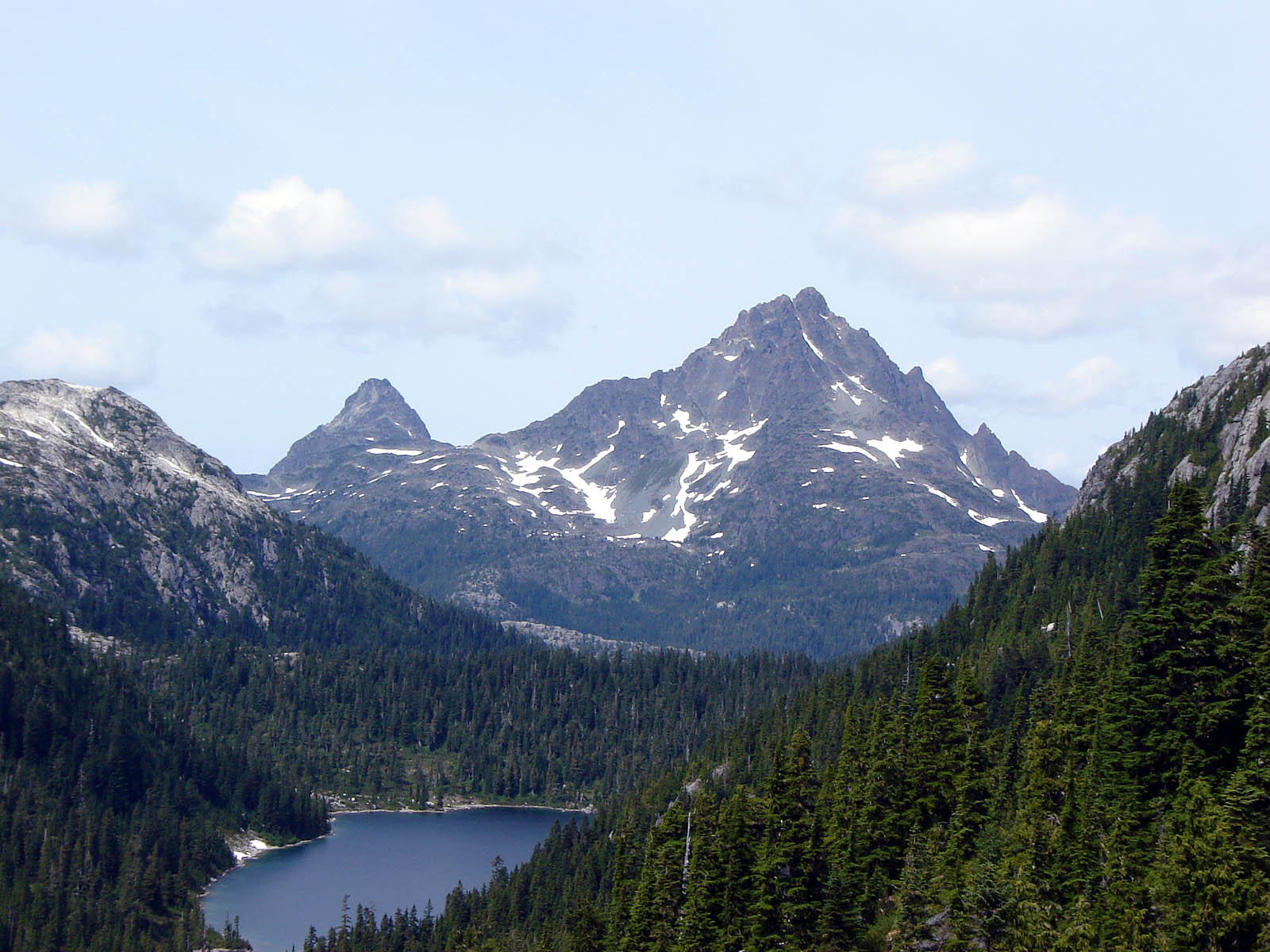 The Golden Hinde, Vancouver Island - a small lake surrounded by mountains covered in trees and snow.