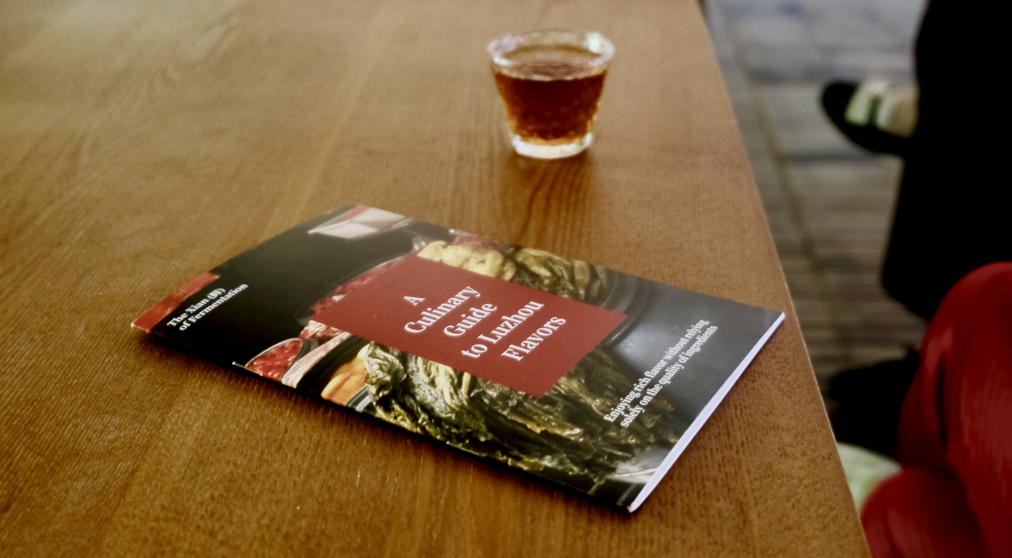 A brochure from Snout & Seek next to a class of tea on a plain brown wooden table.
