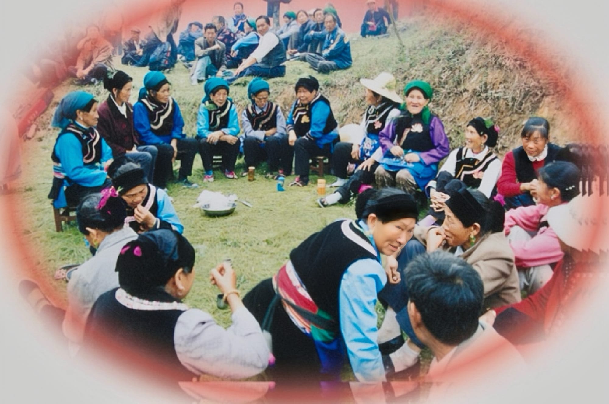 Ethnic Dai women sit in a circle, dressed in their sky blew shirts and black vests.