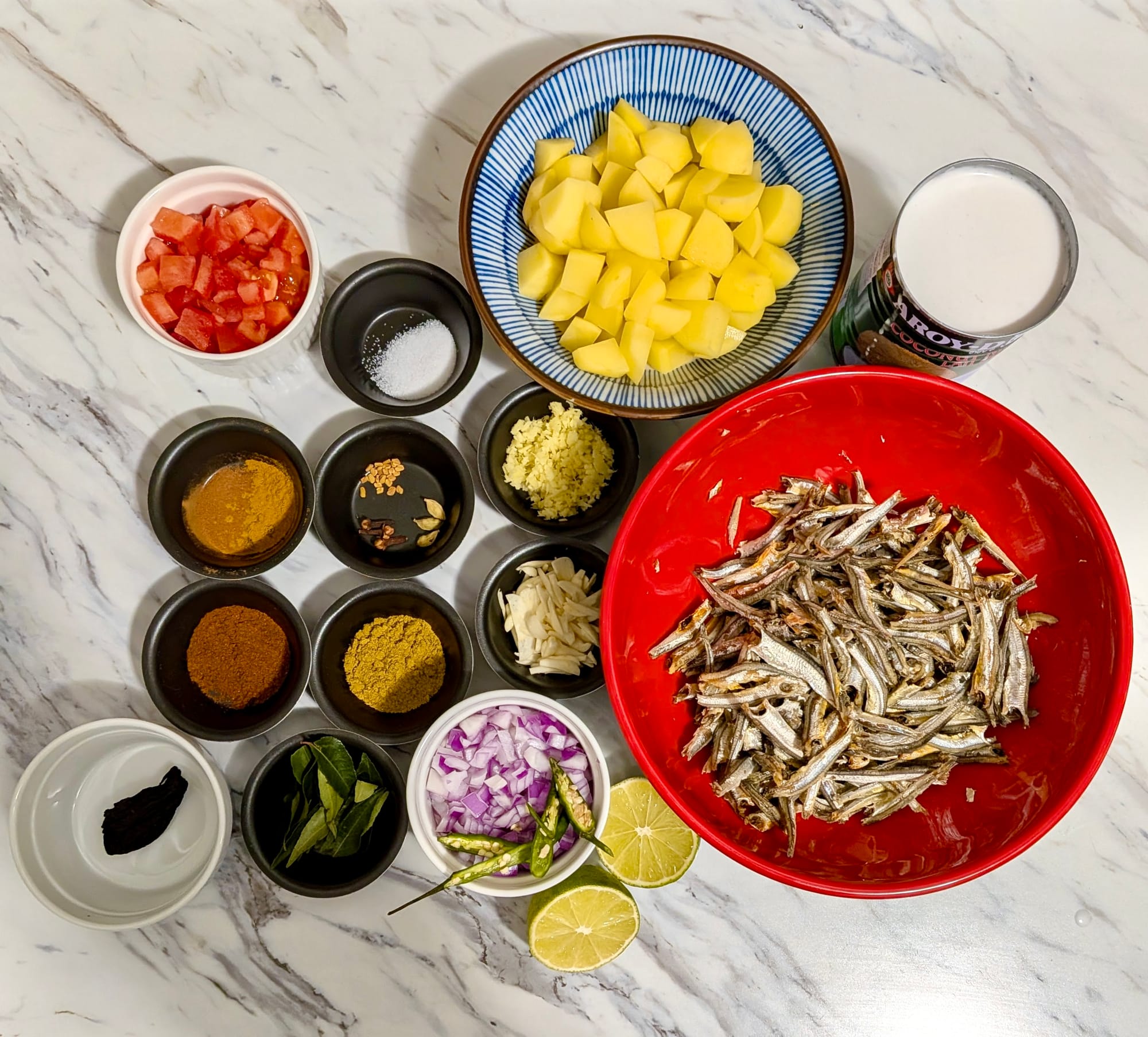 The ingredients for a breakfast curry sit in individual dishes laid out on a white marble countertop.