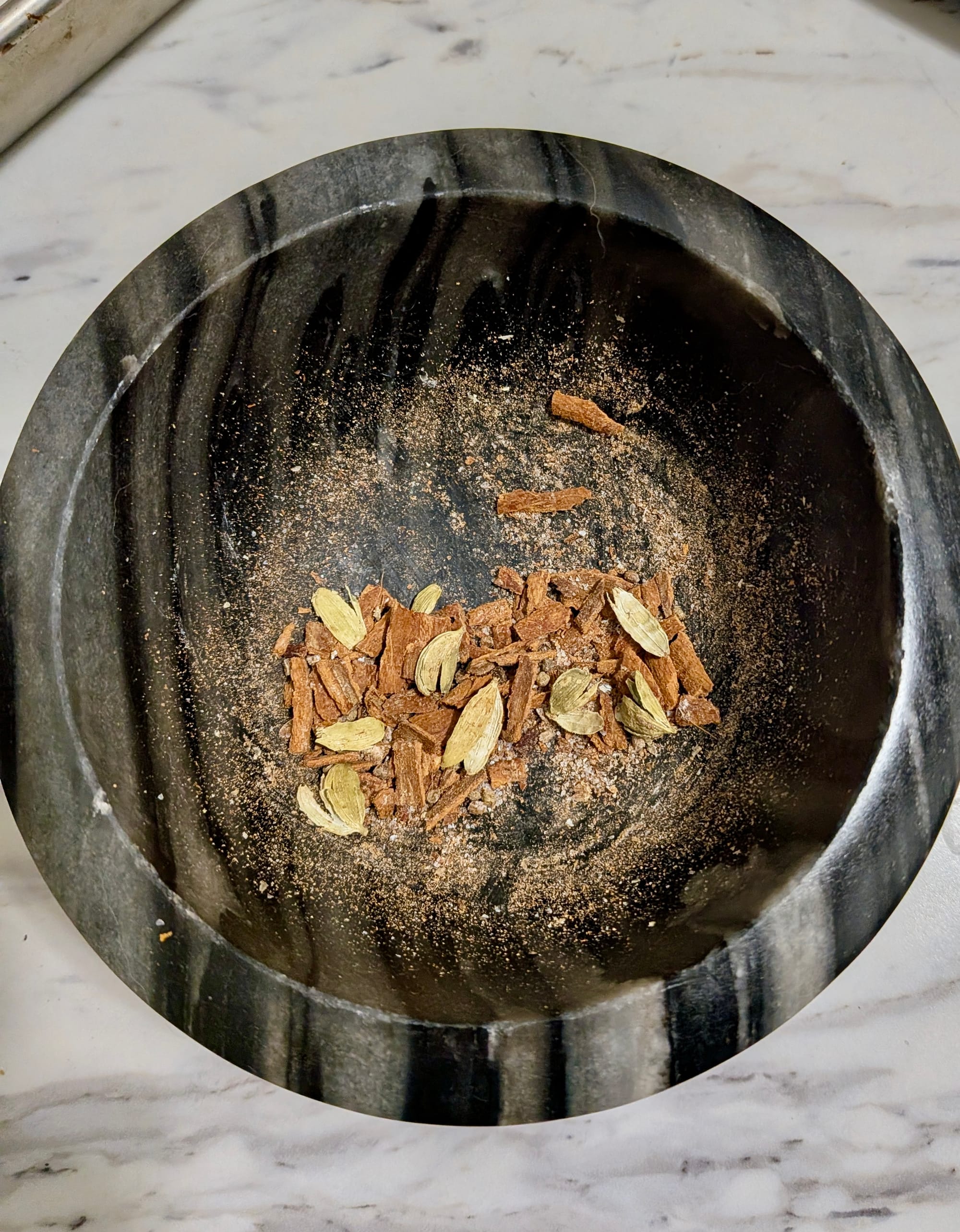 Various spices crushed up into a coarse mix in a mortal and pestle.