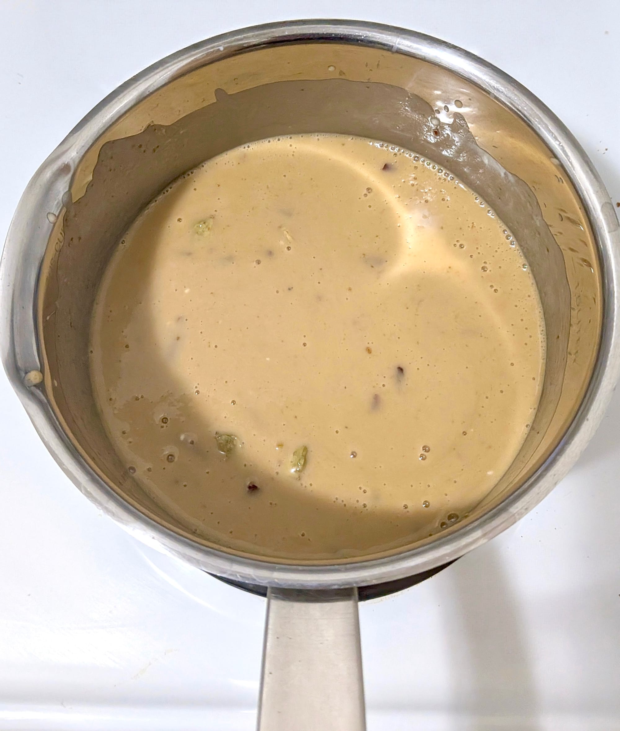 A pot filled with spices, coconut cream, and jaggery - coming to a light brown mixture.