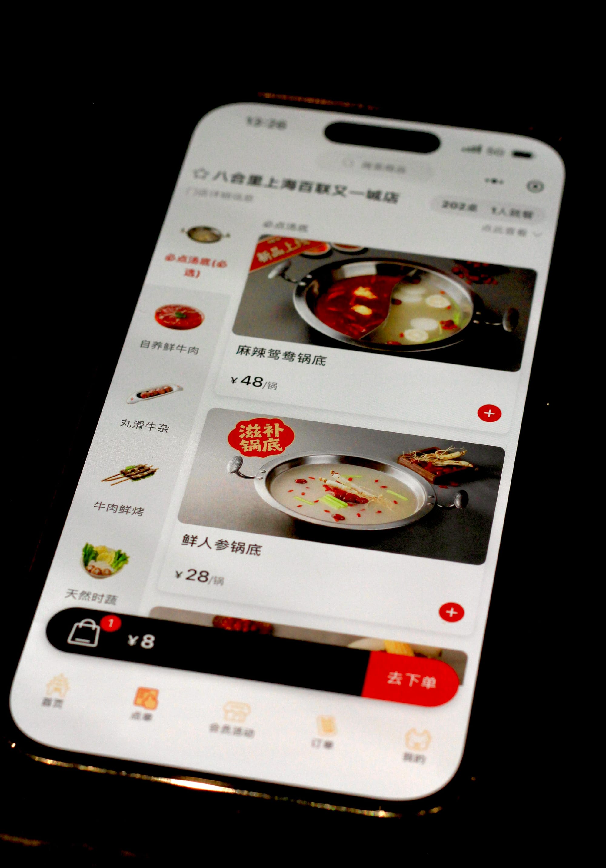A photo of a phone with Meituan, a food delivery application, opened to a menu showing Chinese hotpot soup bases.