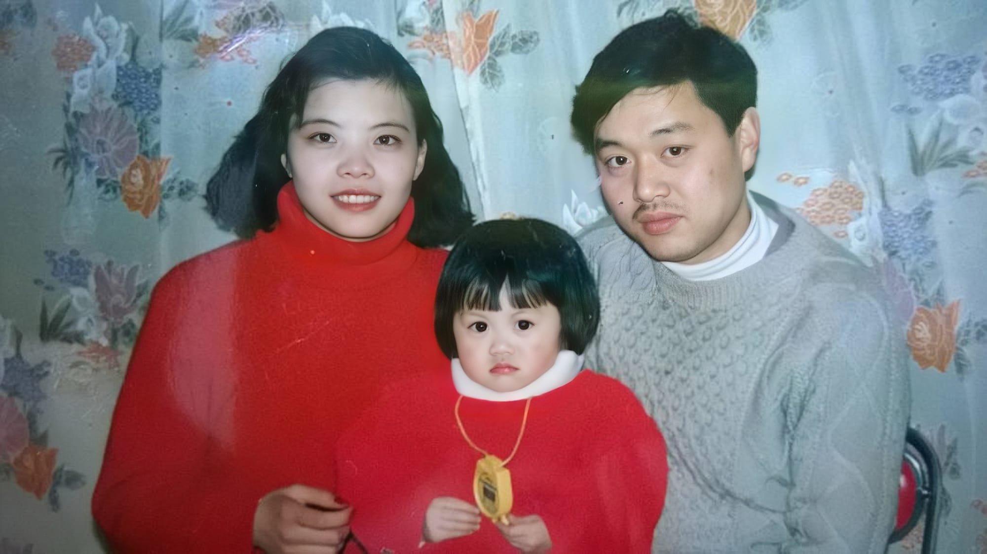 Zhuang Zhuang's family portrait, her as a child, posing with her mother and father. Her and her mother wear matching red shirts.