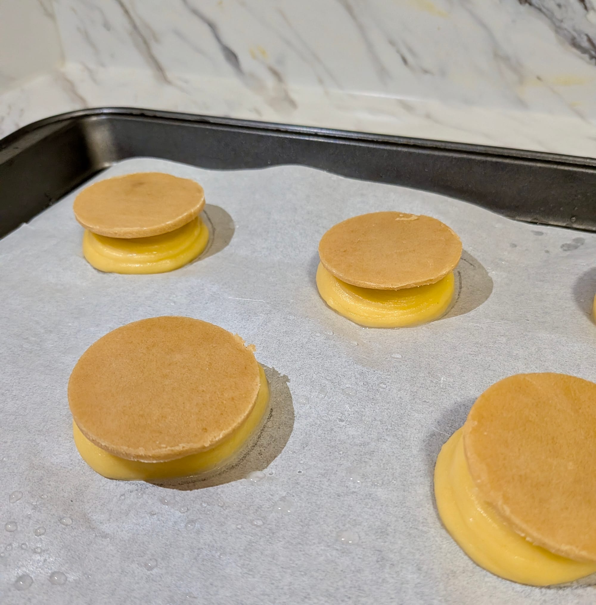 Choux cones with craquelin disks on top sitting on parchment paper about to enter the oven.