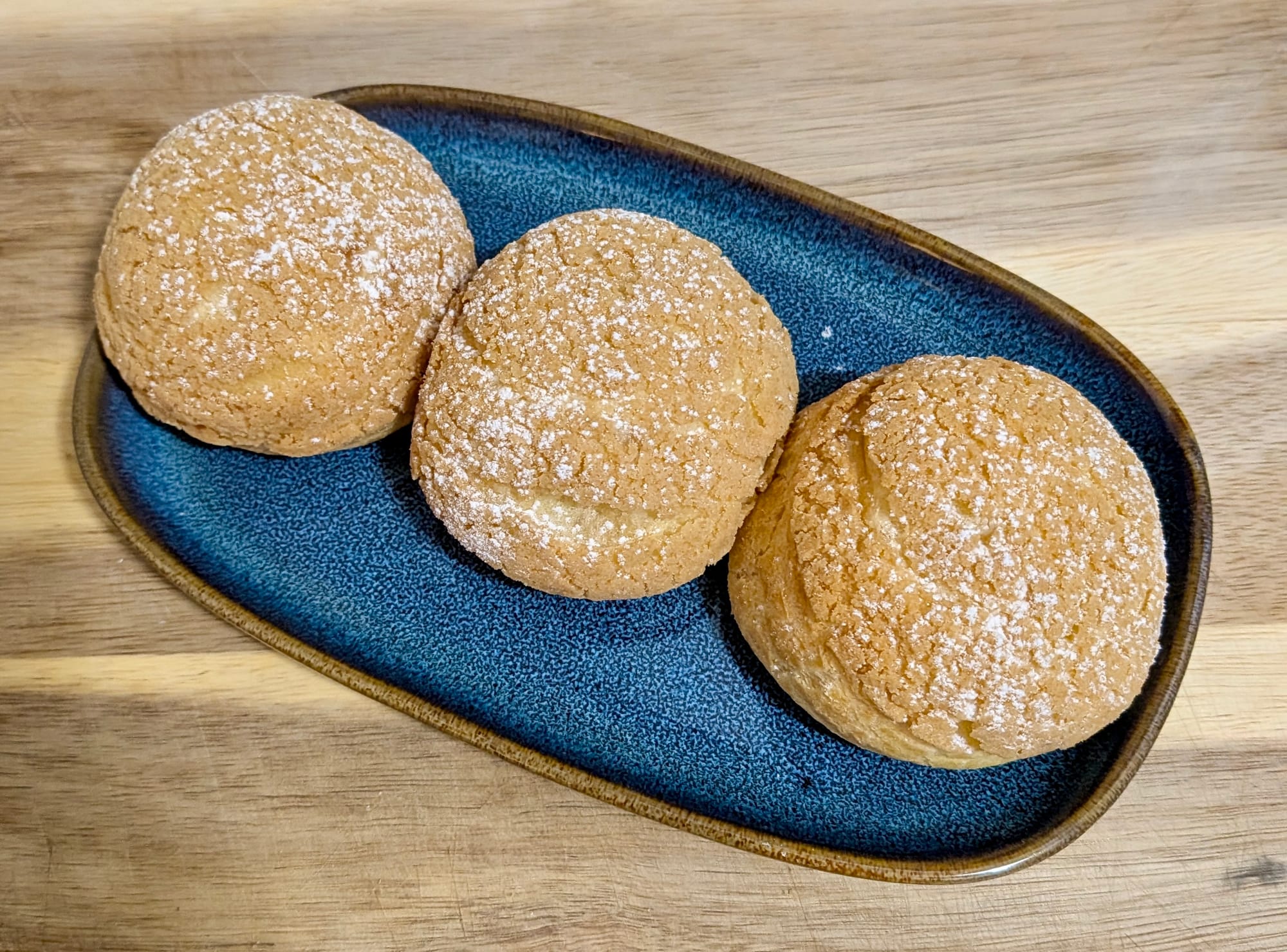 Three Lemongrass Petite Choux with icing sugar atop.