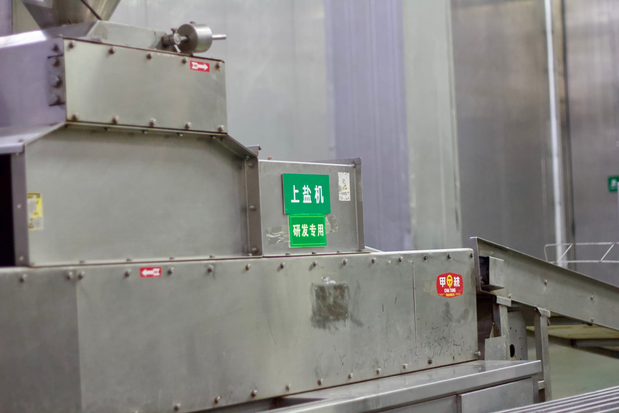 A steal industrial machine used to tenderize pork in a factory.