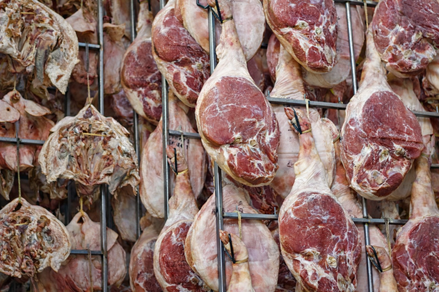 Shanks of pork hang on racks inside a drying room.
