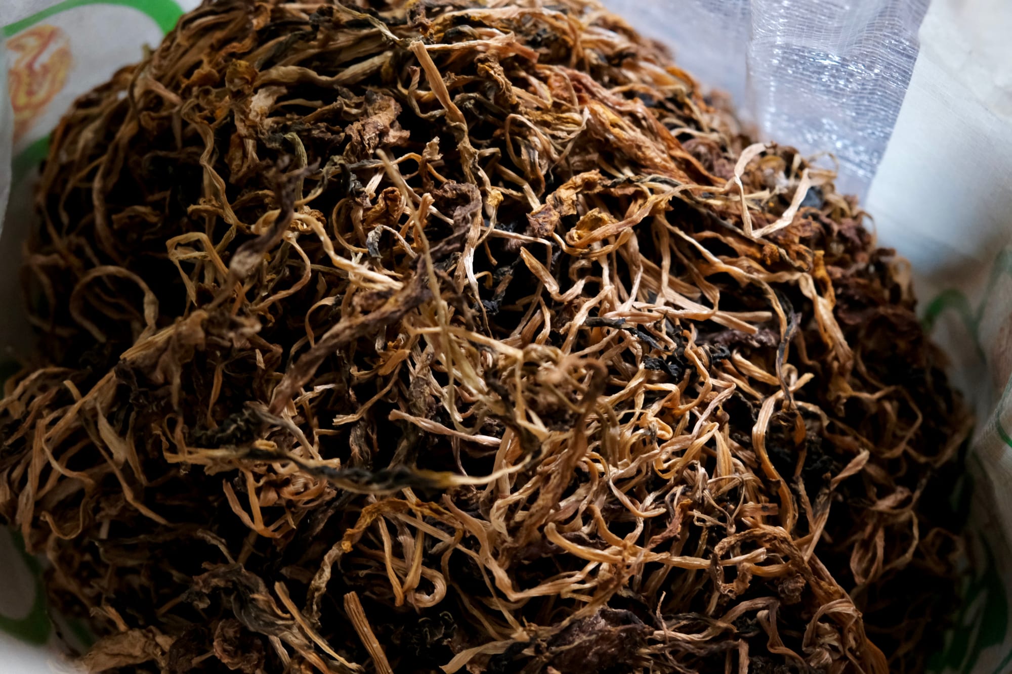 Sun-dried pickled greens in a pile, looks similar to dried tea leaves or fungus.