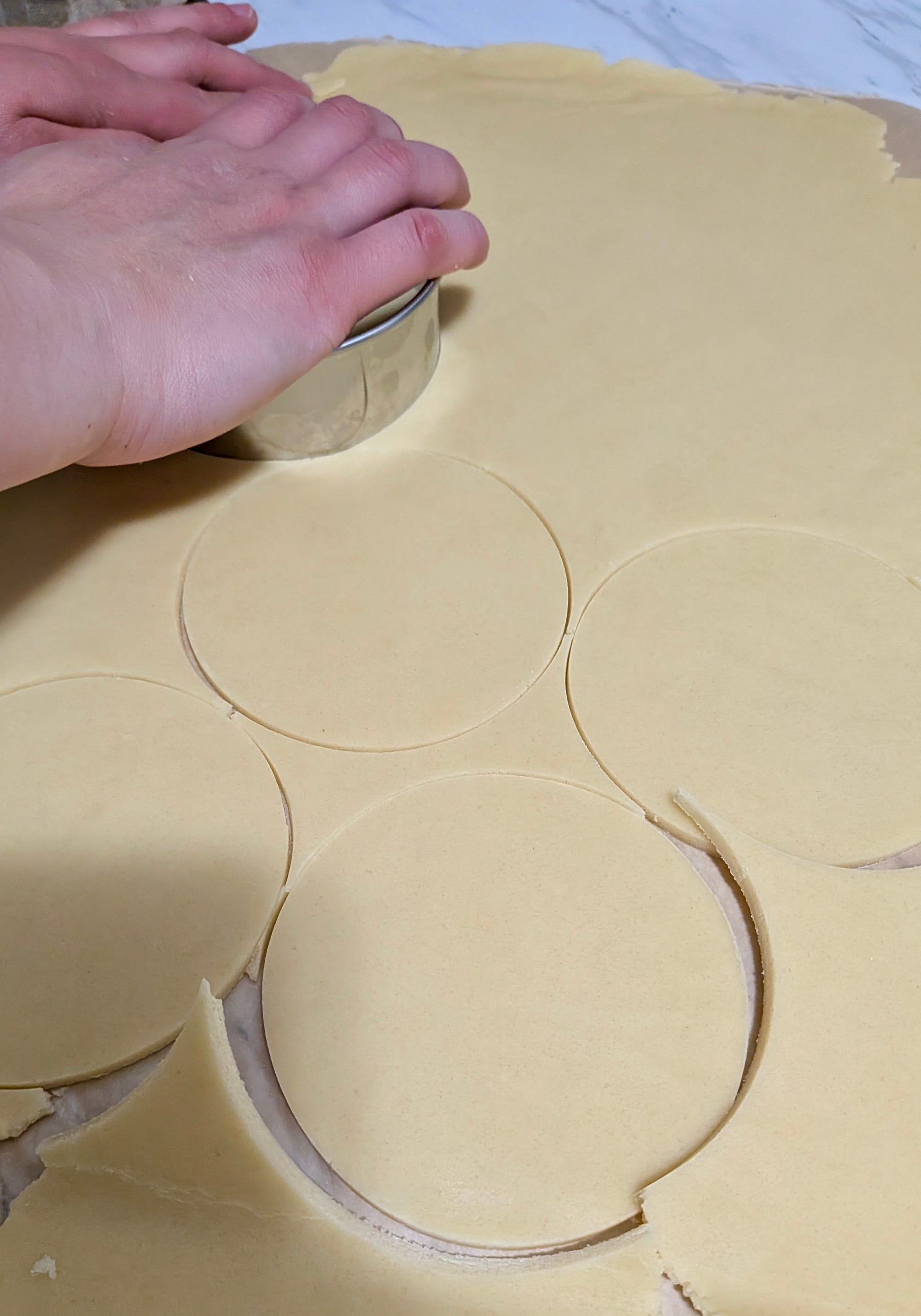 A thin dough sheet being cut into circular disks.