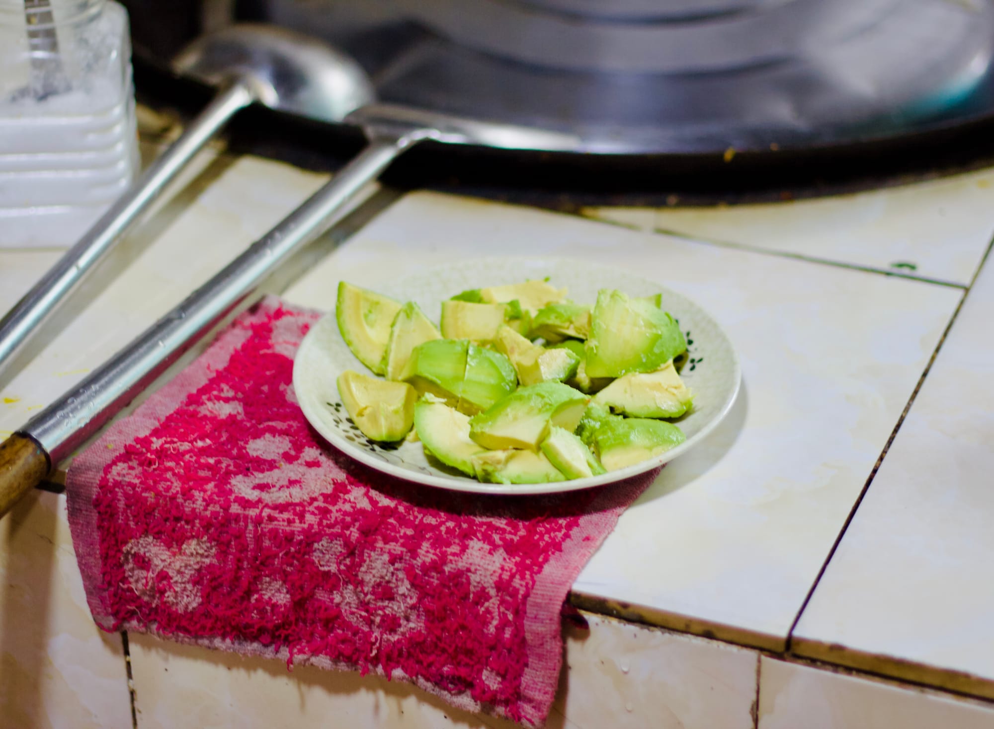 Diced avocados on a plate next to a traditional giant Chinese wok.
