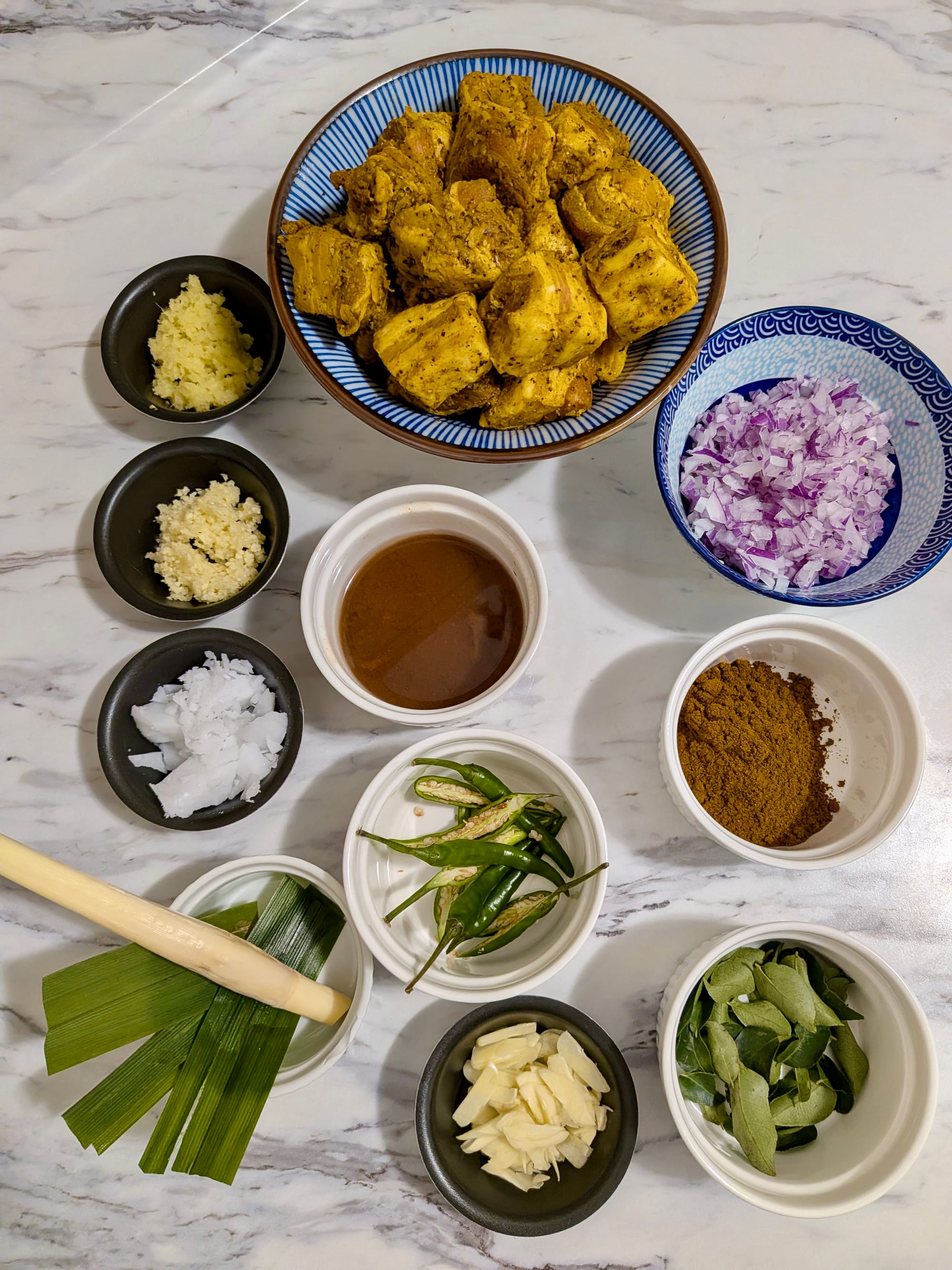 Portioned ingredients organized neatly in little dishes for Sri Lankan Black Pork Curry