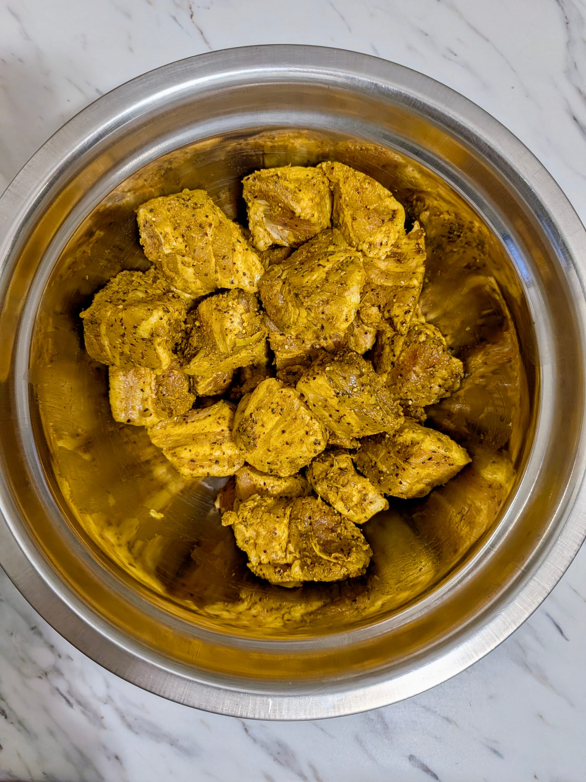 Black pork cubed and rubbed with a Sri Lankan curry marinade in a stainless steel bowl