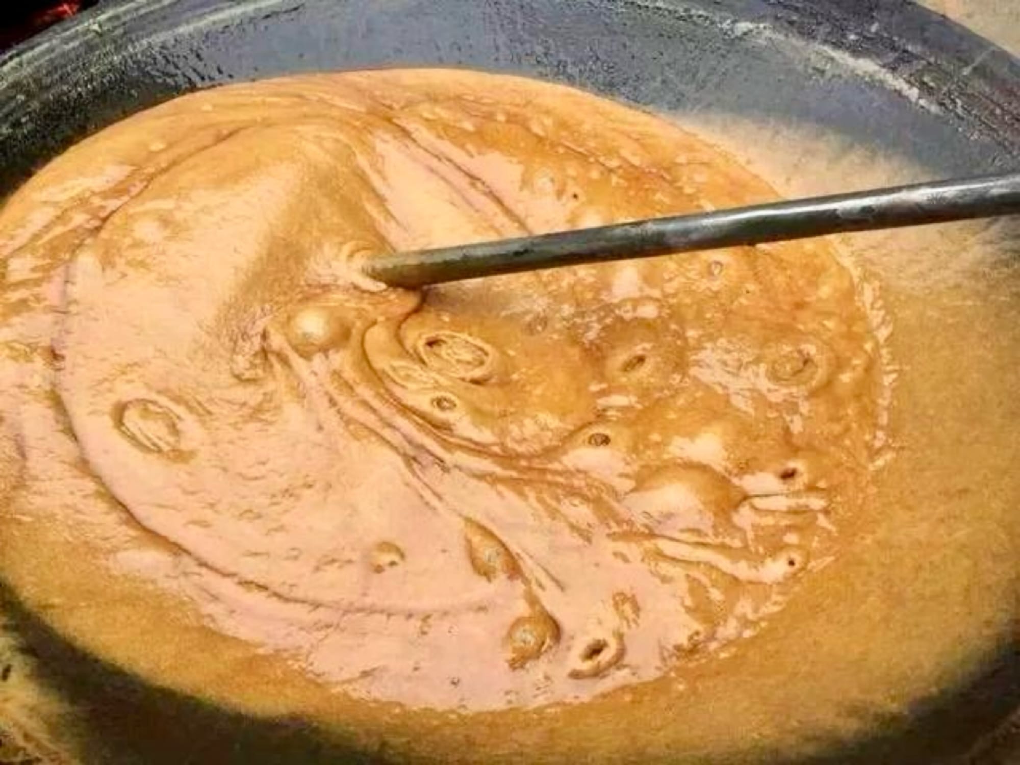 Boiling sugar down, a thick light-brown viscous liquid fills the pot.