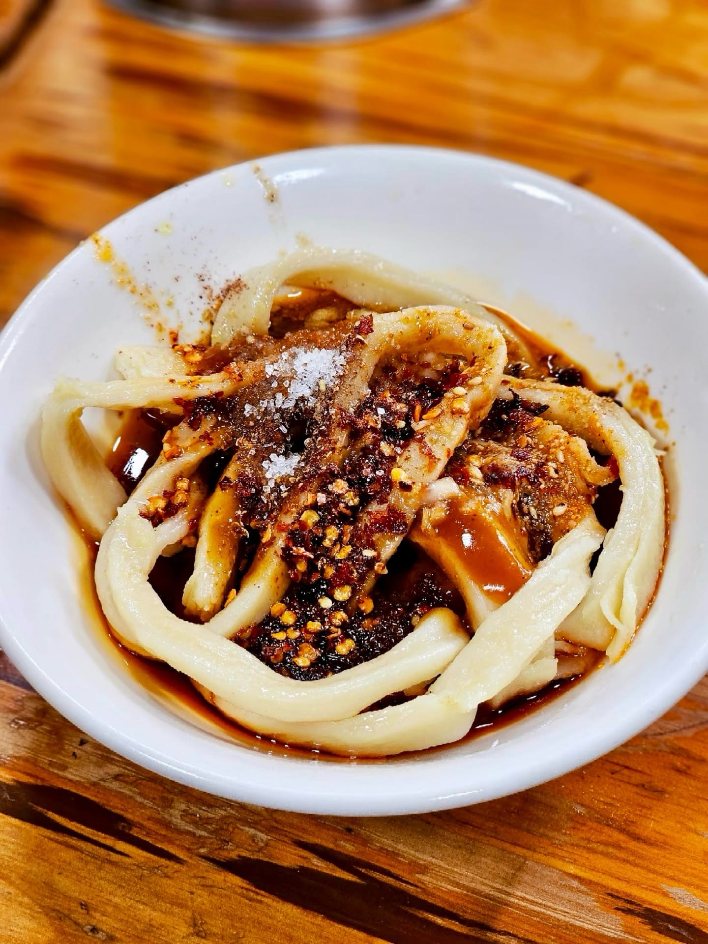 Tian Shui Mian, or Sweet Water Noodles - thick white noodles covered in a dry spice and brown sugar rub, placed in a white bowl.