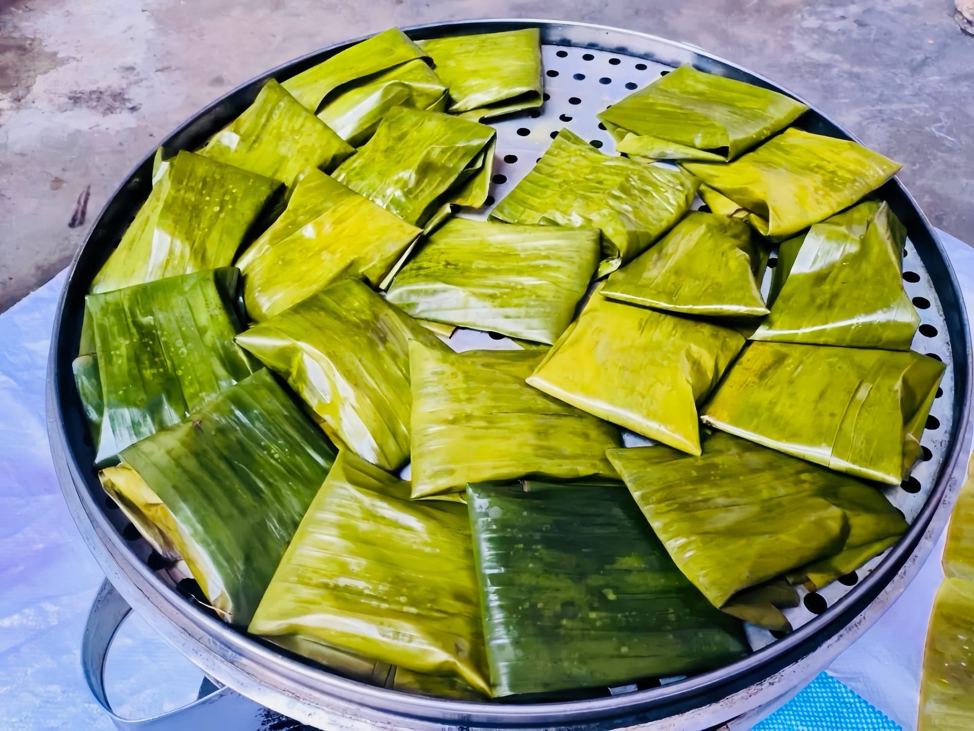 Bamboo leaf sachets on a steaming plate, inside contains rice with brown sugar.