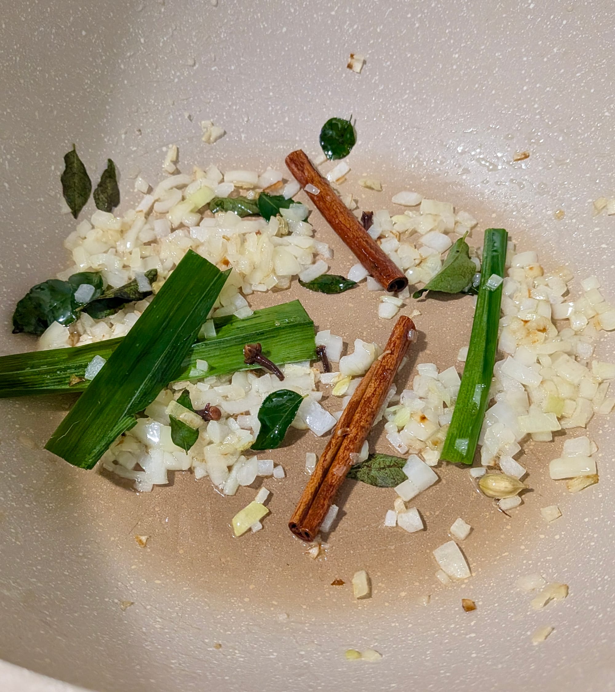 Sweating onions, cinnamon, and lemon grass in a pan.