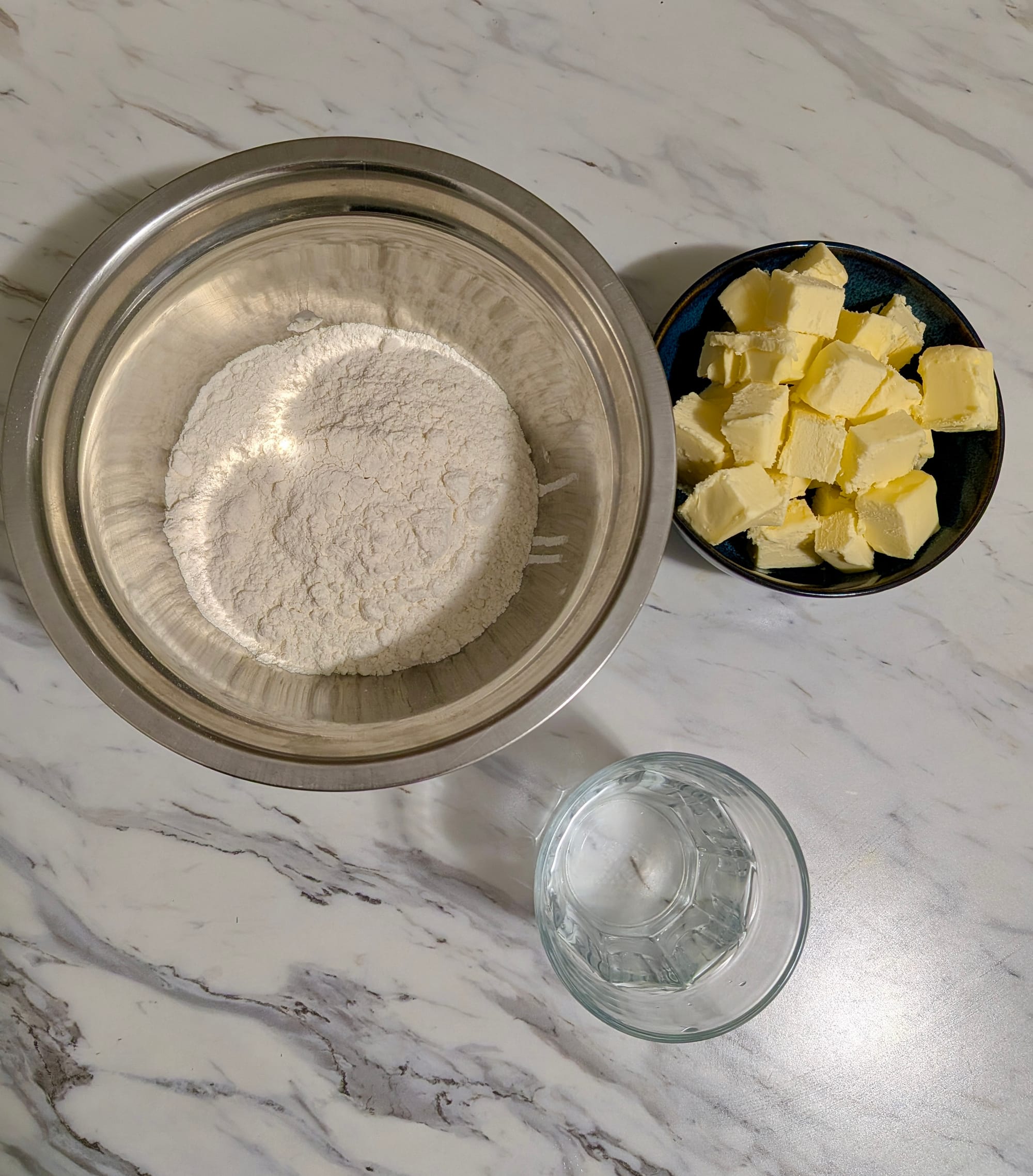 Flower, water, and cubed butter in individual portioned dishes to make dough.