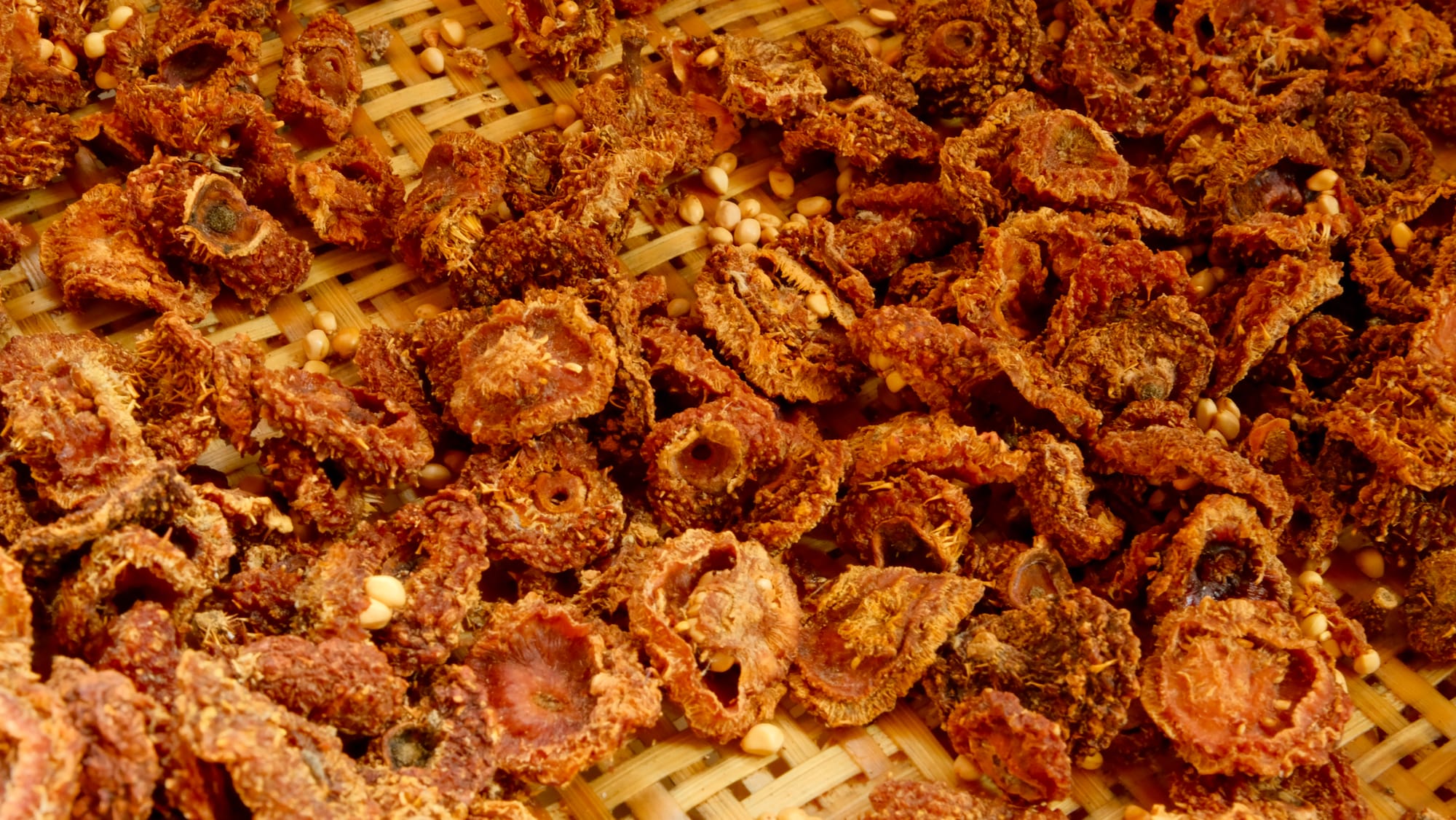 Redish-orange dried cili fruits on a bamboo basket.