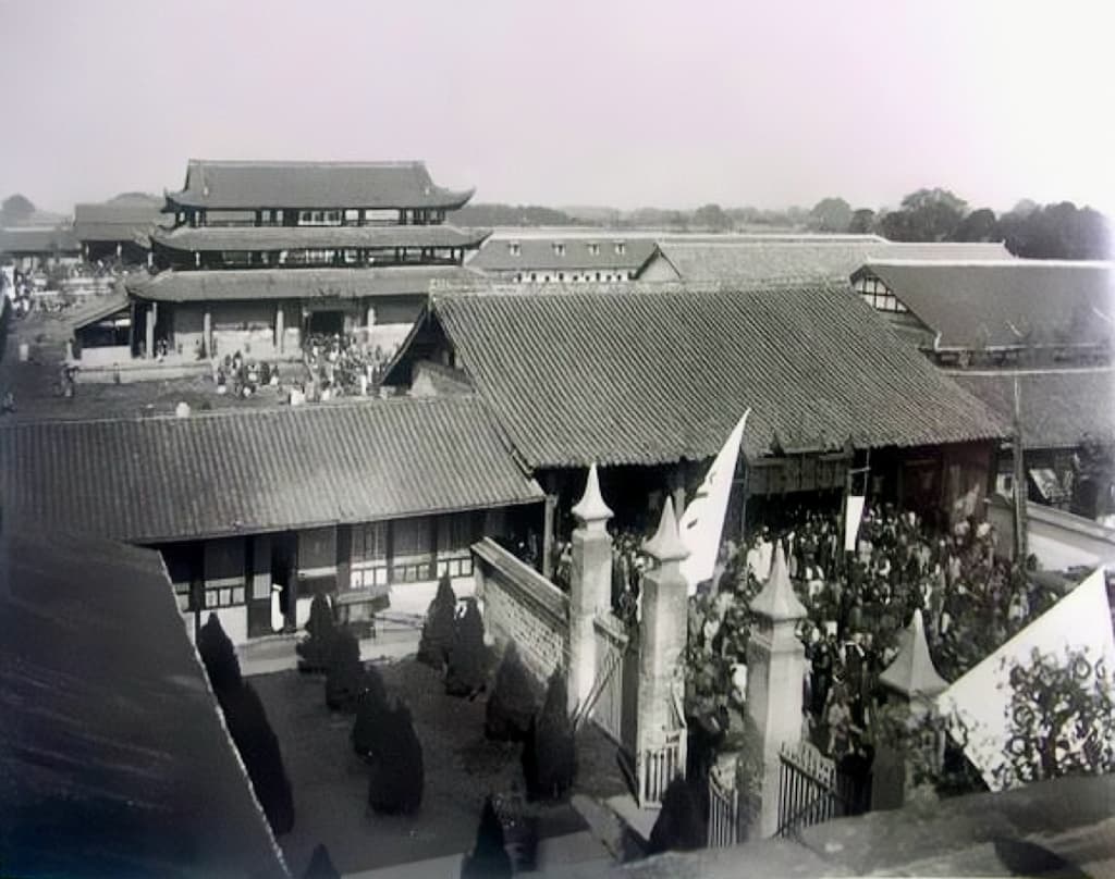 A black and white photograph of an ancient Chinese community home - traditional courtyards surrounded by slate-rooved buildings.