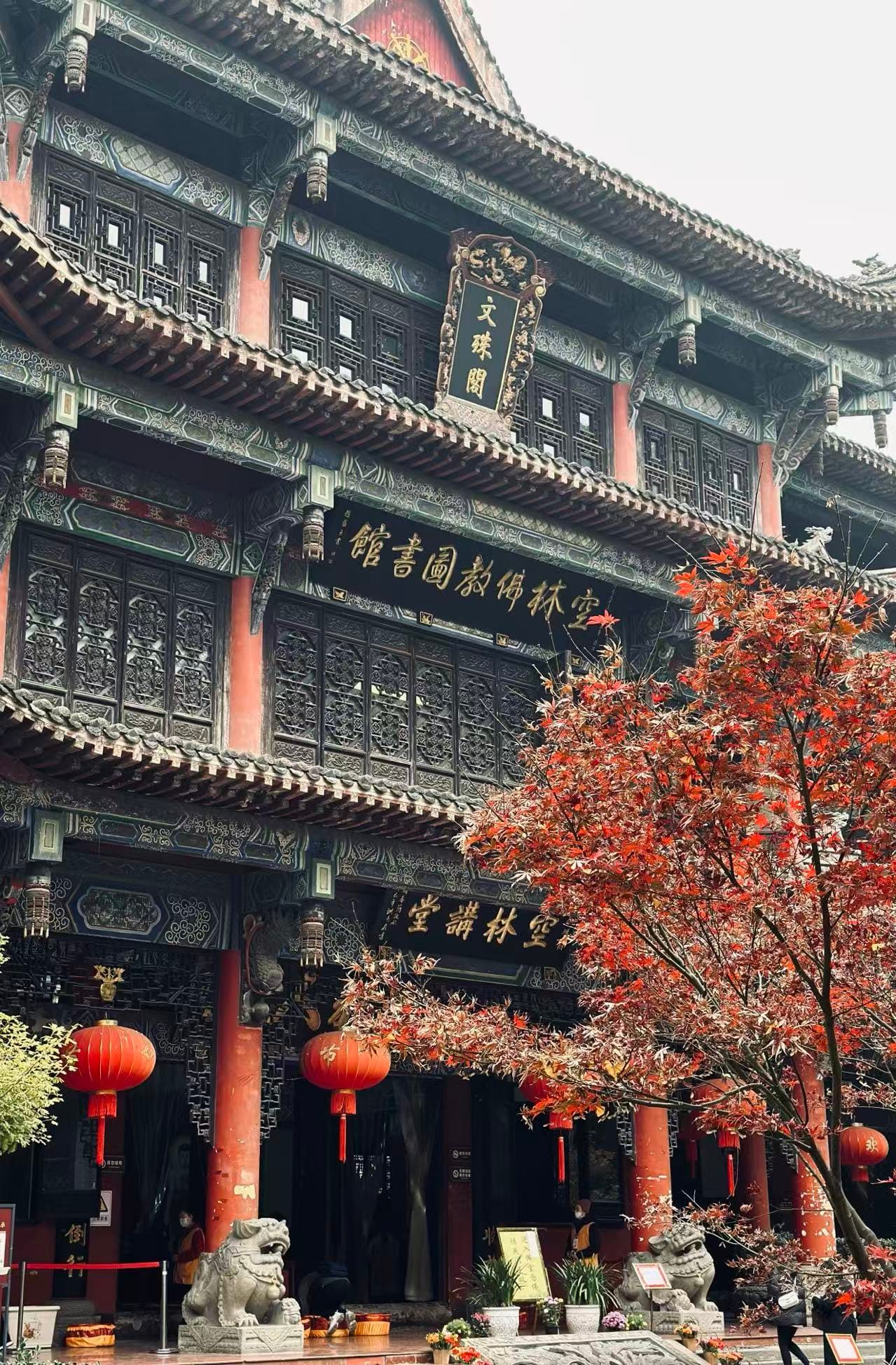 Wenshu Monastery in Chengdu - a large three story building with very intricate and detailed wood carvings in the details all over the windows, eaves, pillars, and doors.