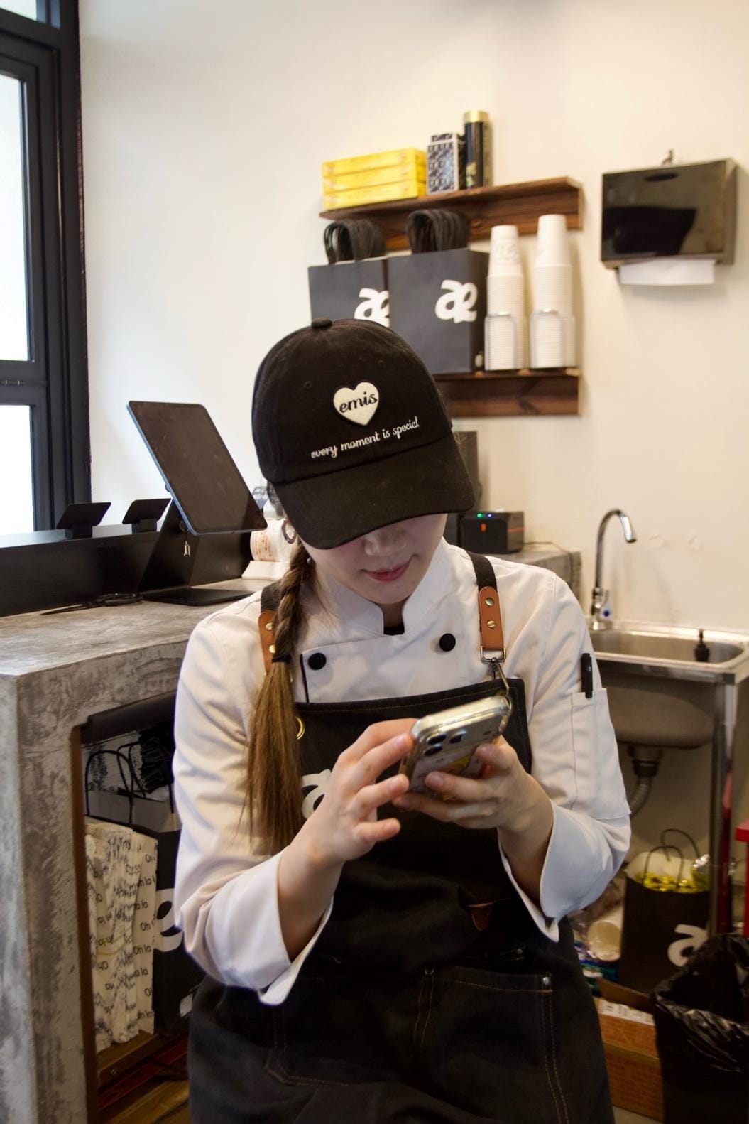 Ally Jiang checking her phone in the middle of her bakery before she begins for the day.