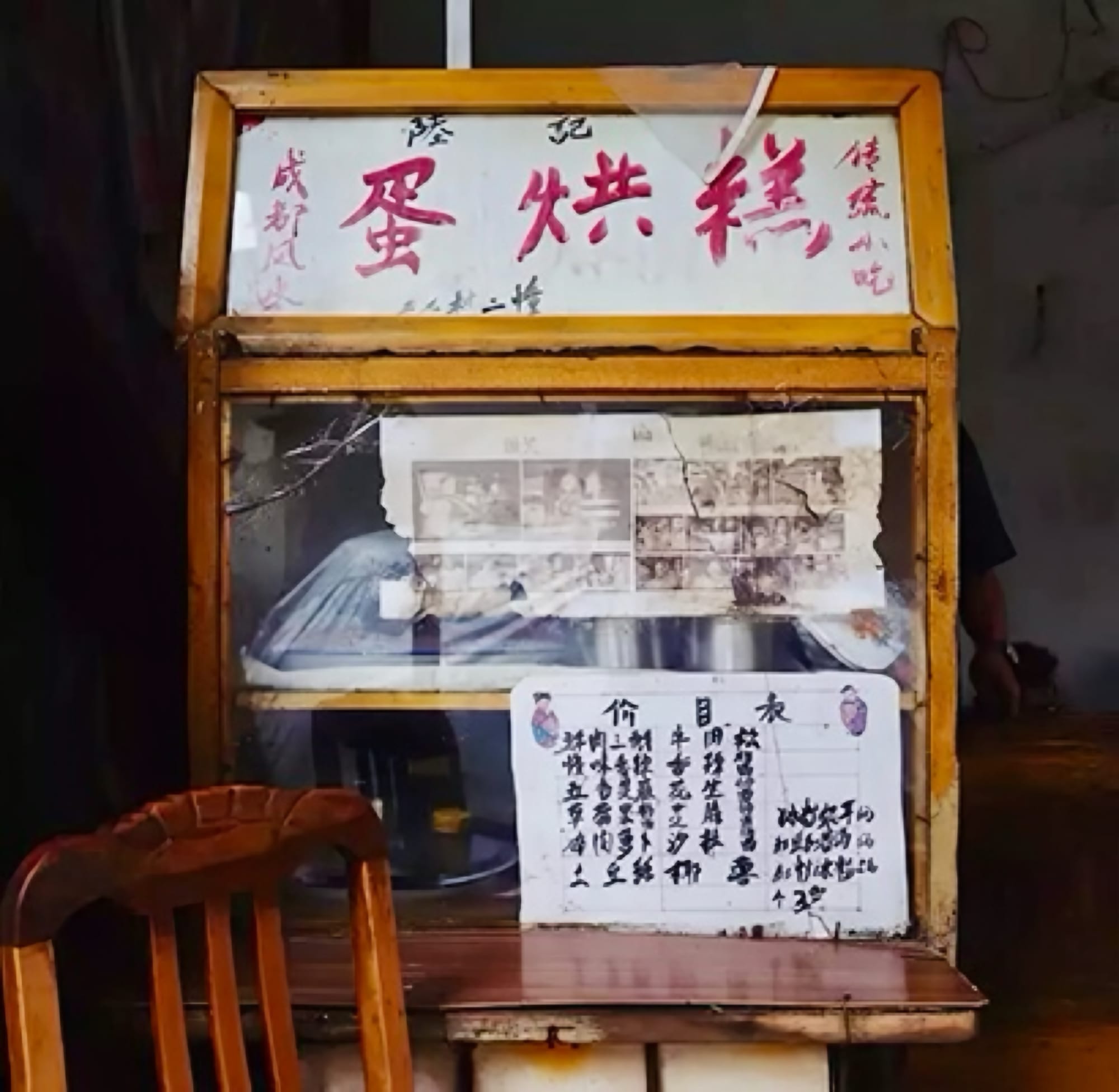 An old street stall window with worn out news paper clippings and a small sign from the owner detailing what they make behind the window.