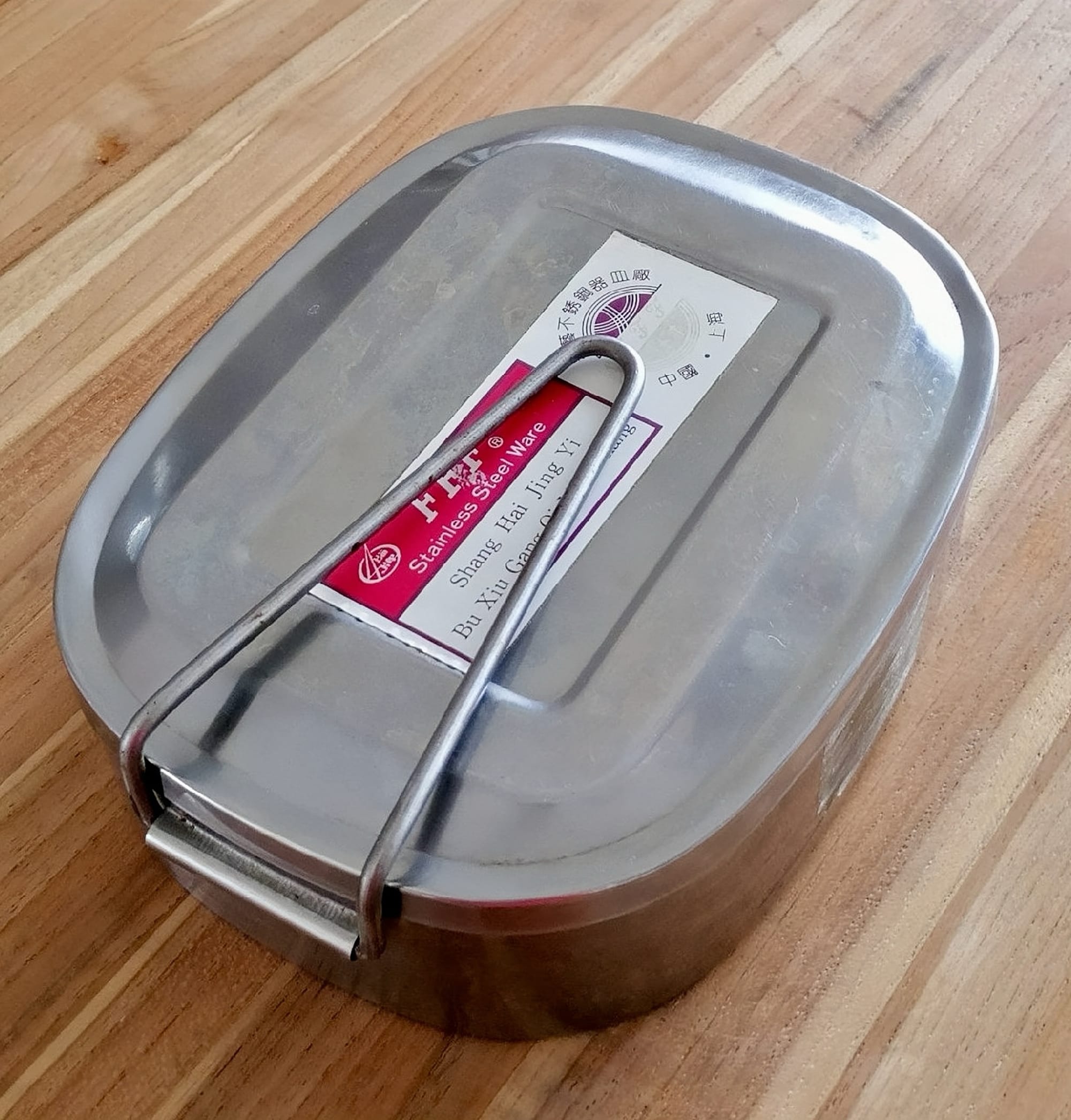 A silver tin with a metal clasp over it, similar to a sardines can, but larger.