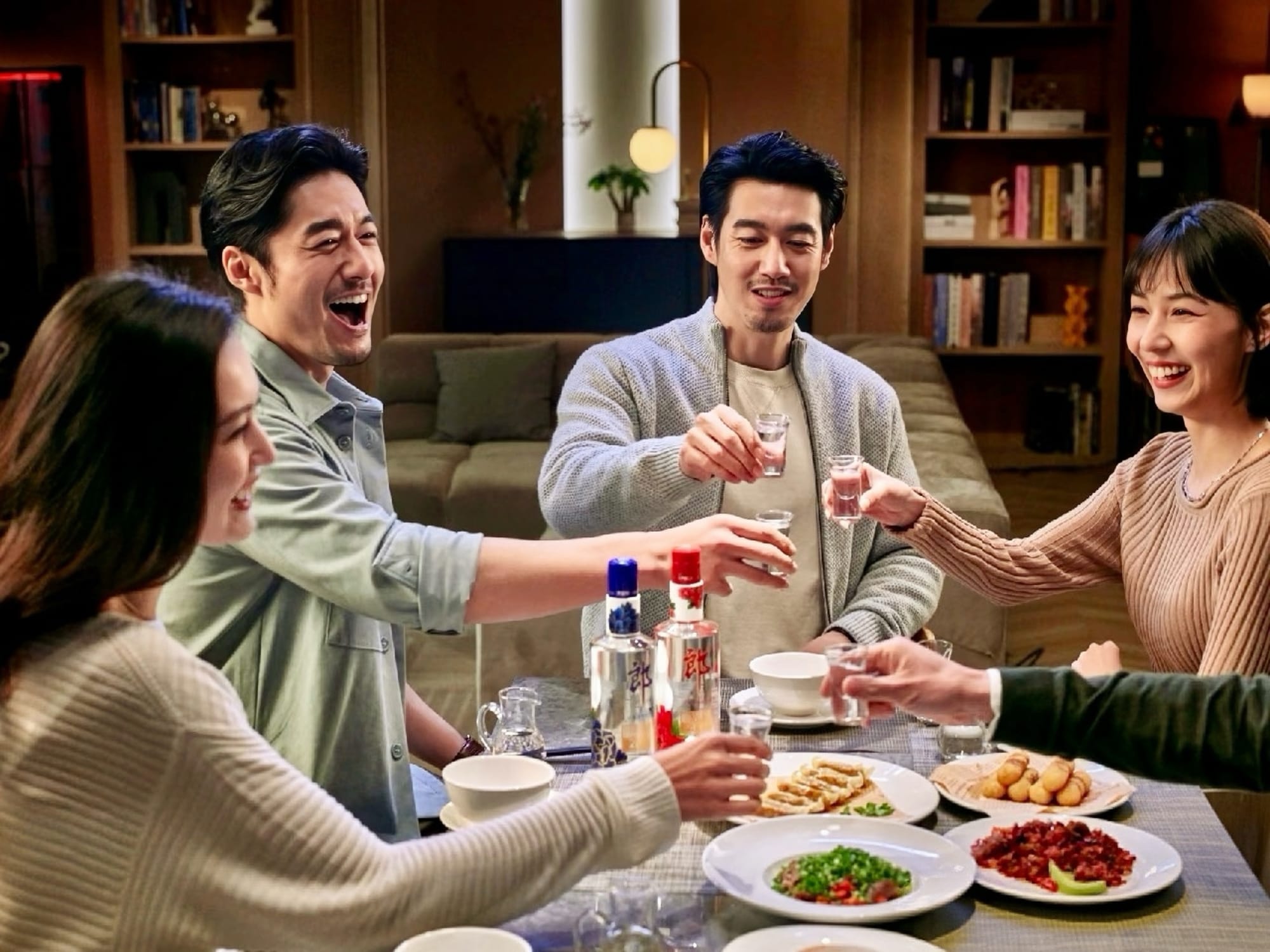 Four Chinese people - two women; two men, sitting at a table with various dishes, clinking baijiu glasses in a toast.