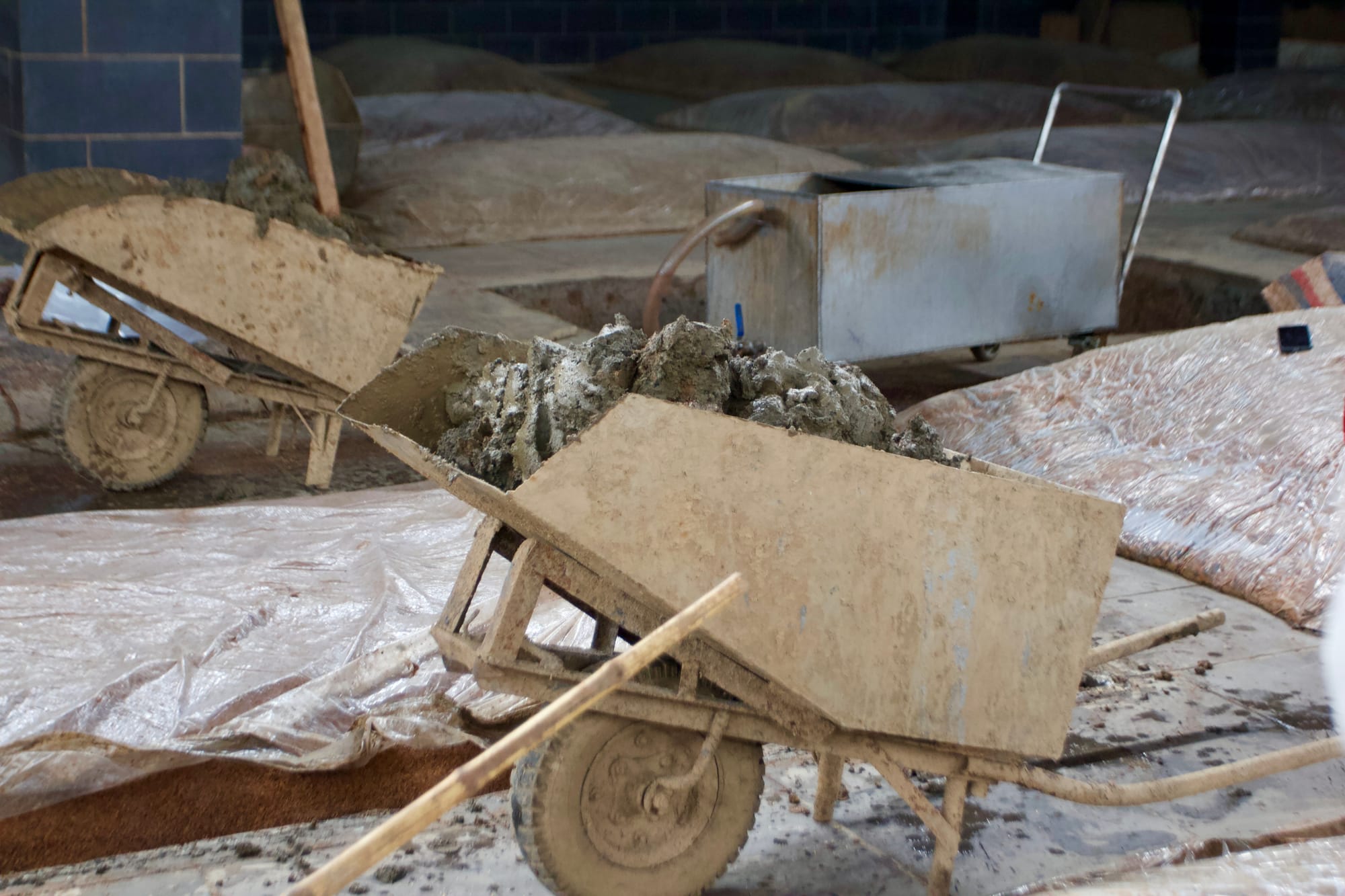 Wheel barrows filled with mud in a baijiu fermentation pit.