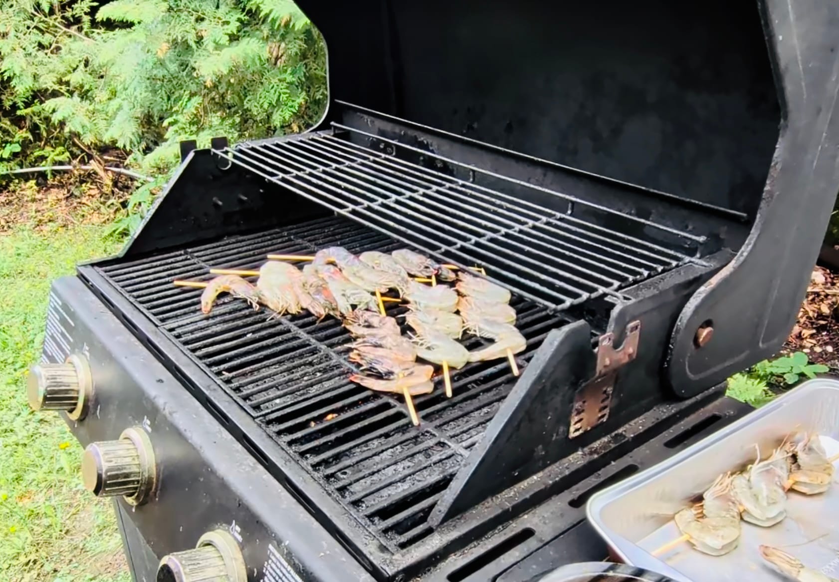 A BBQ grill with 6 prawn skewers grilling.