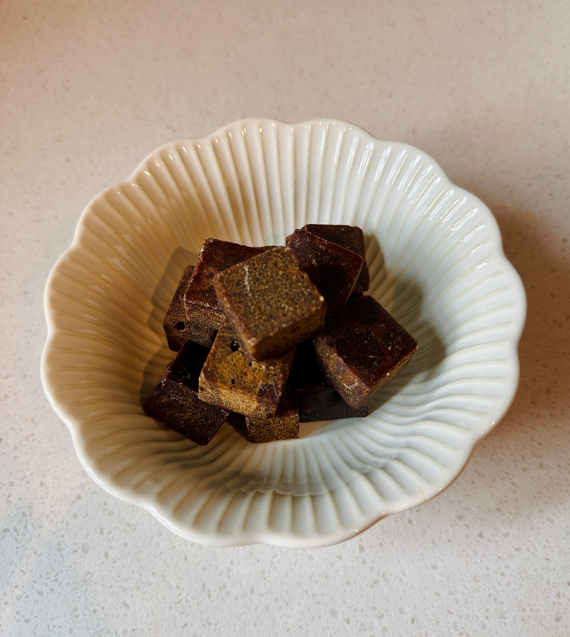 A white dish filled with red/brown sugar cubes.