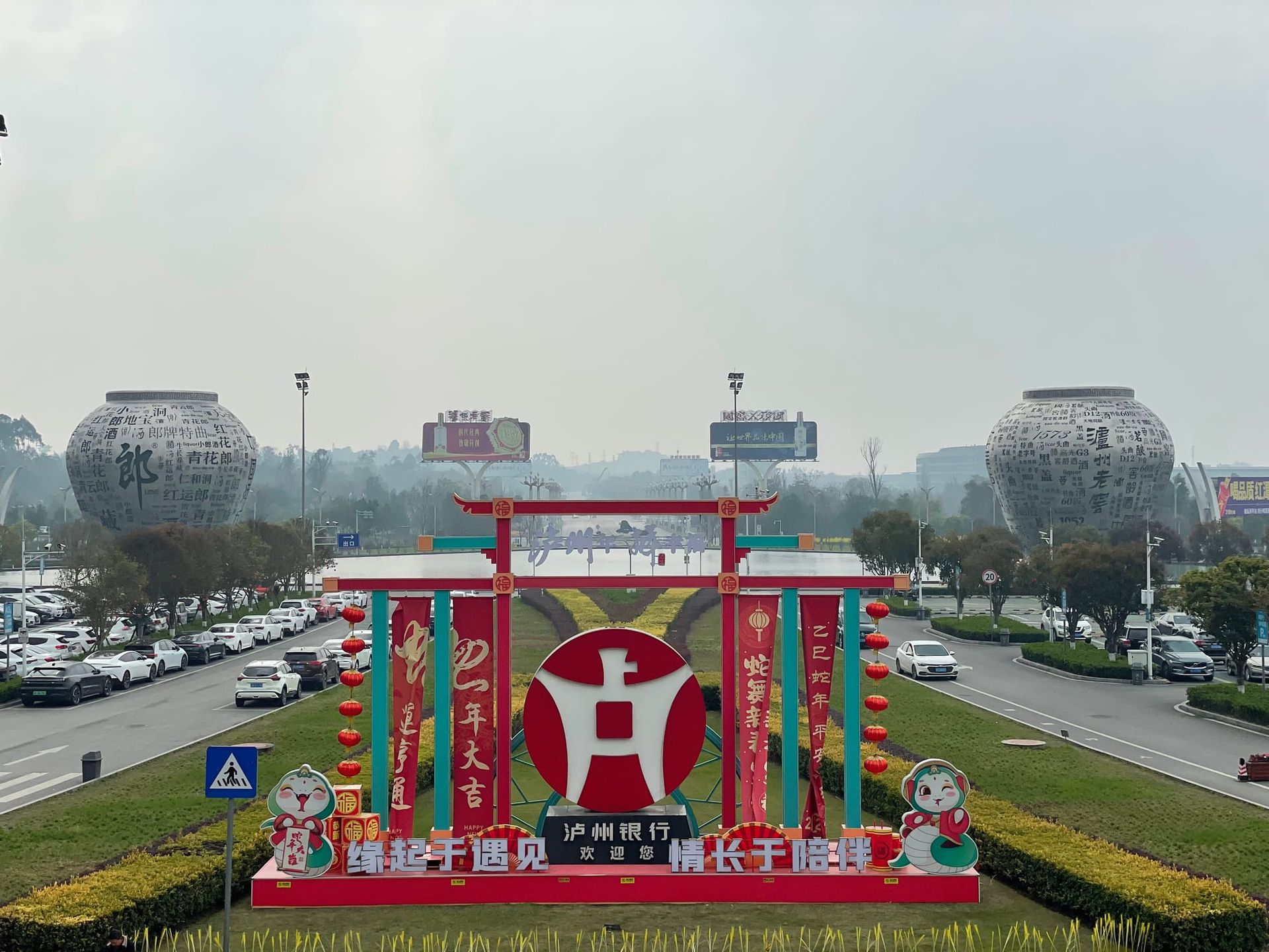 Two building-sized baijiu urns flank the roads leading to and from the Luzhou airport. In the centre is a big red sign welcoming people to Luzhou.